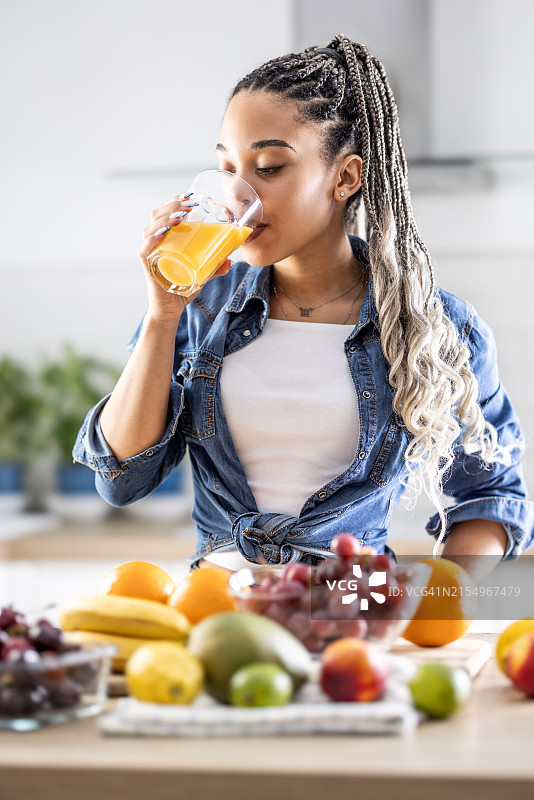 一位迷人的年轻女士正在喝由新鲜水果制成的健康复合维生素果汁图片素材