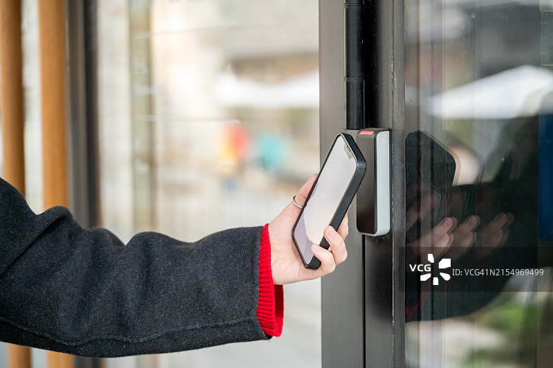 手持智能手机通过智能数字锁开门图片素材