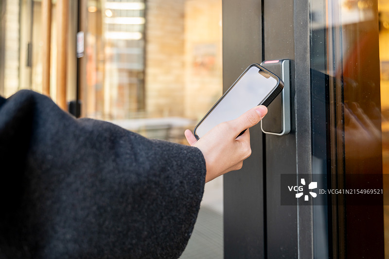 手持智能手机通过智能数字锁开门图片素材