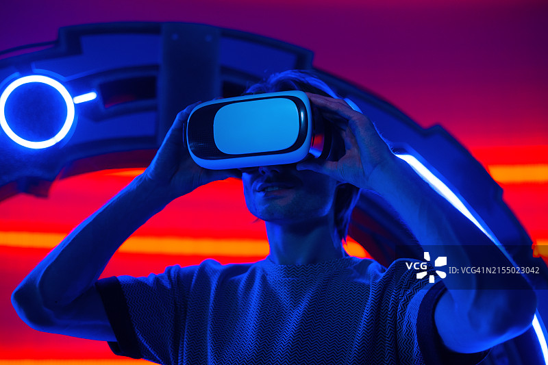 佩戴VR眼镜的未来感男人，背景是霓虹灯房间图片素材