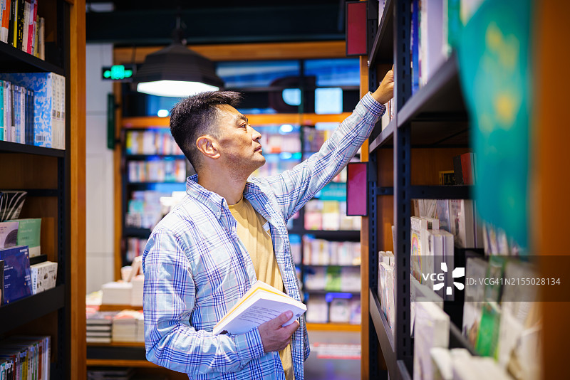在城市公共图书馆借阅书籍的亚洲中年男人图片素材
