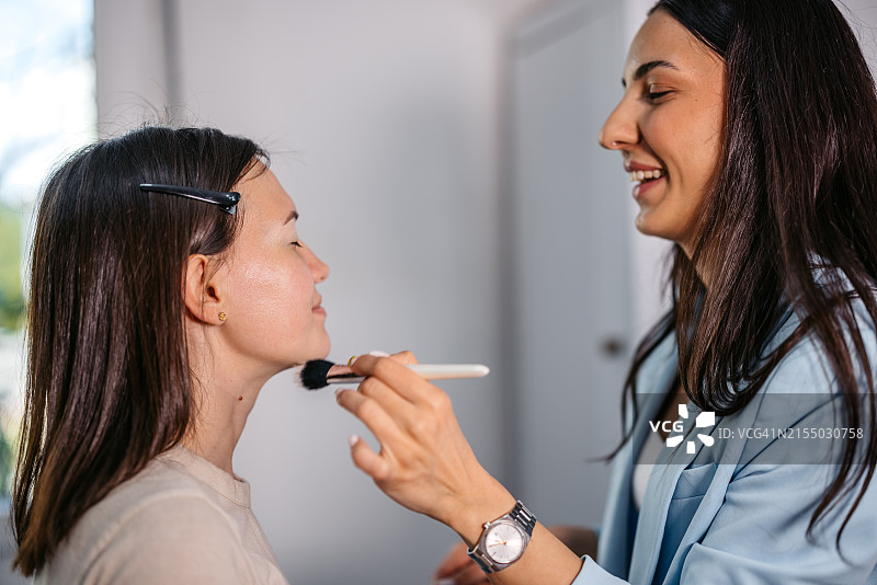 化妆师在美容院用化妆刷为顾客上粉底液图片素材