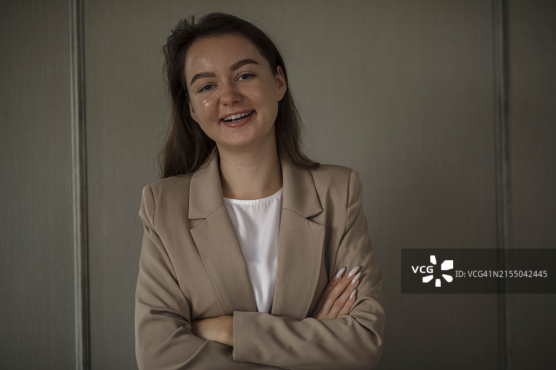 微笑的女商人，一位小企业主在她的办公室里双臂交叉站立图片素材
