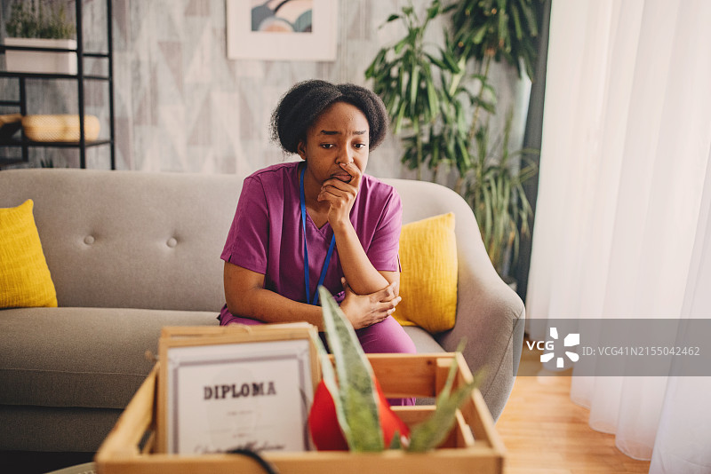 拿着文凭和搬家纸箱的沉思护士图片素材