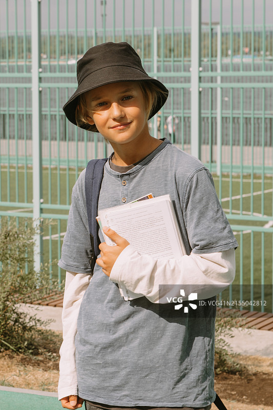 在学校操场上拿着课本微笑的男孩图片素材