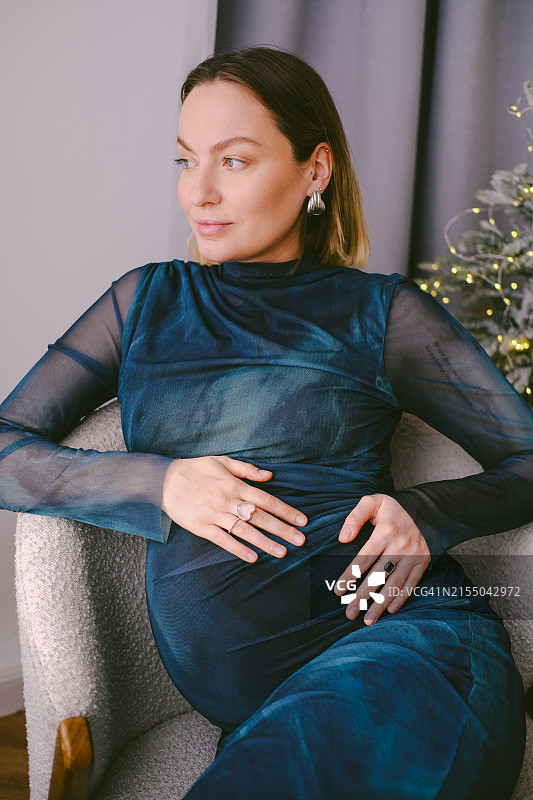 穿着复古裙子的快乐年轻孕妇抚摸着肚子图片素材