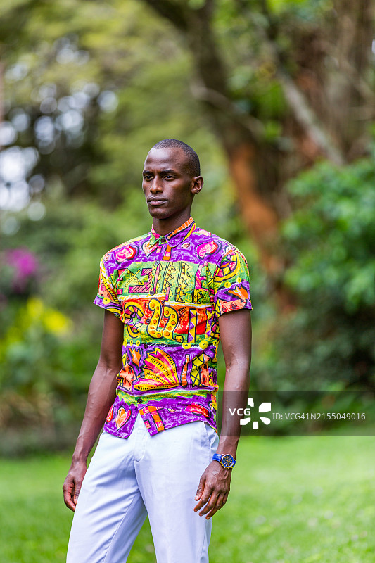 在自然环境中穿着传统衬衫摆姿势的年轻非裔美国男子图片素材