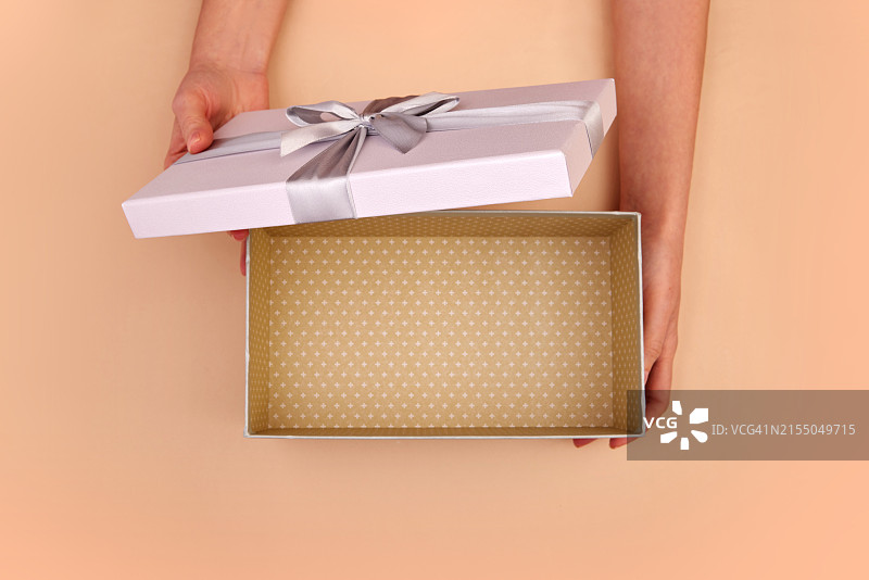 在桃色背景上打开带有礼品蝴蝶结的盒子，顶视图图片素材