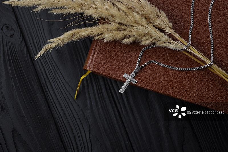 黑色木桌上带有十字架的银色项链和基督教圣经图片素材