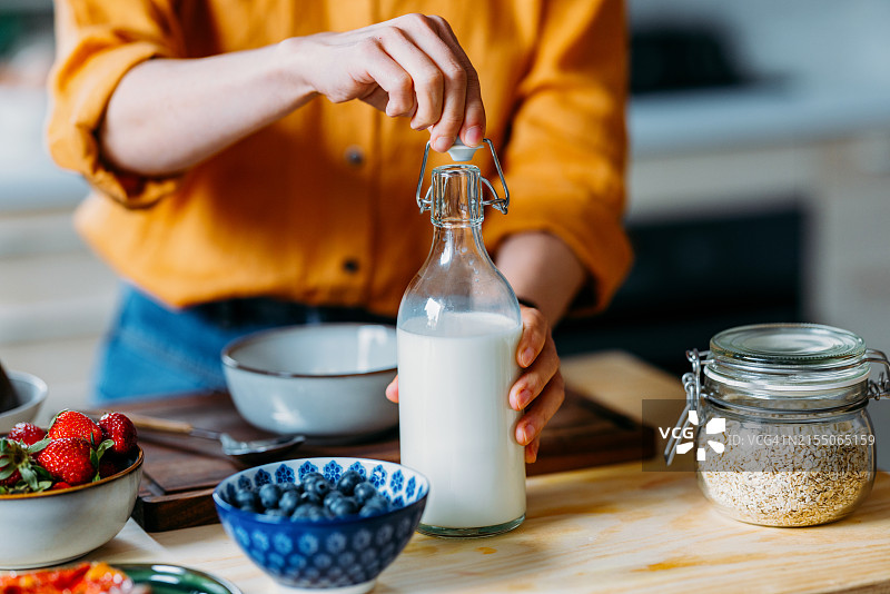 准备含鲜牛奶和浆果的健康早餐的人图片素材