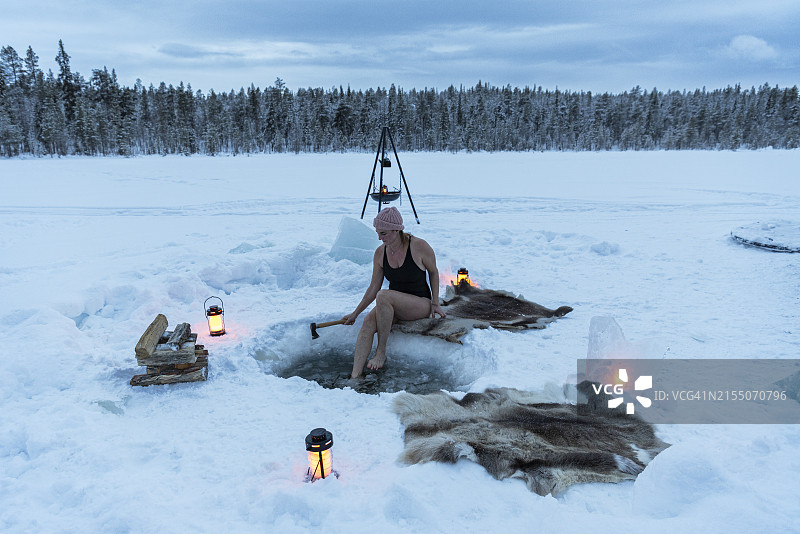 女人在黄昏时分在冰冻的湖面上进行冰浴，地点：Jokkmokk，Norrbotten，瑞典拉普兰，瑞典，斯堪的纳维亚，欧洲图片素材