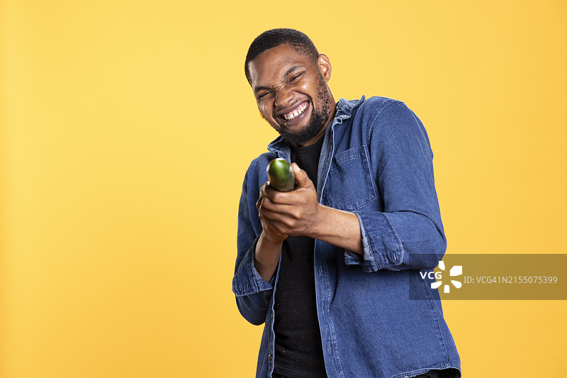 黄色背景上手拿瓶子的微笑男人肖像图片素材