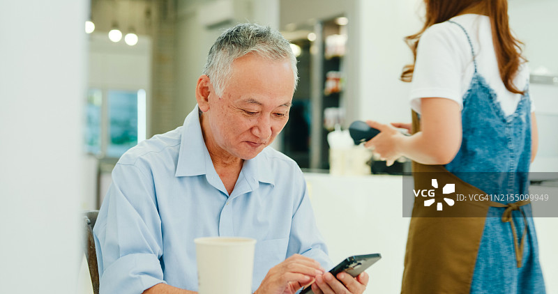 老年亚洲男顾客在咖啡馆手机支付图片素材