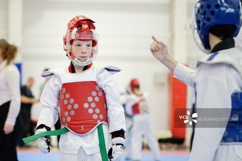 男孩跆拳道比赛：专注的选手与裁判，室内体育馆锦标赛图片素材