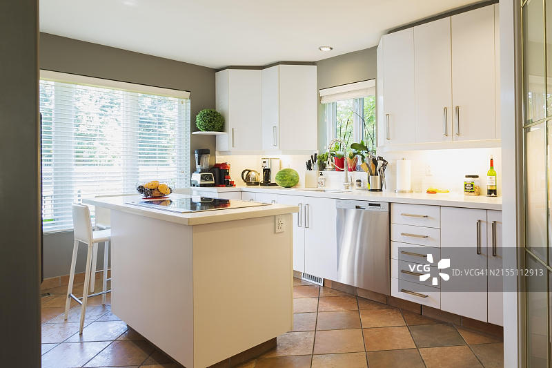魁北克豪华住宅厨房：白色橱柜、石英台面、玻璃灶台岛台和高脚吧台凳图片素材