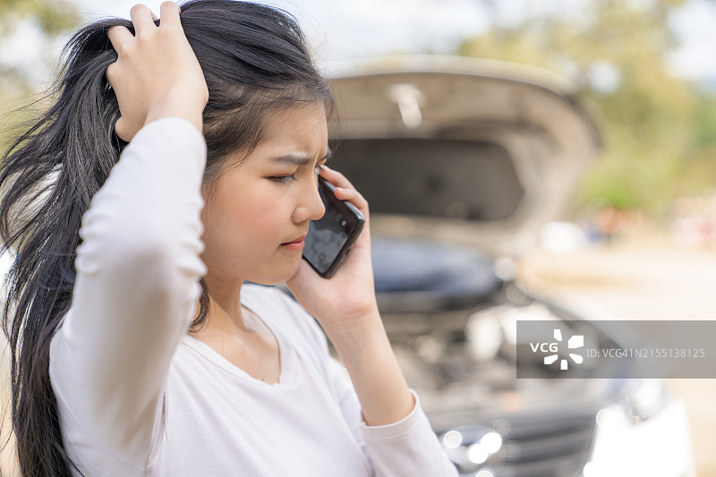 车在路上抛锚，正在打电话求助的年轻女人图片素材