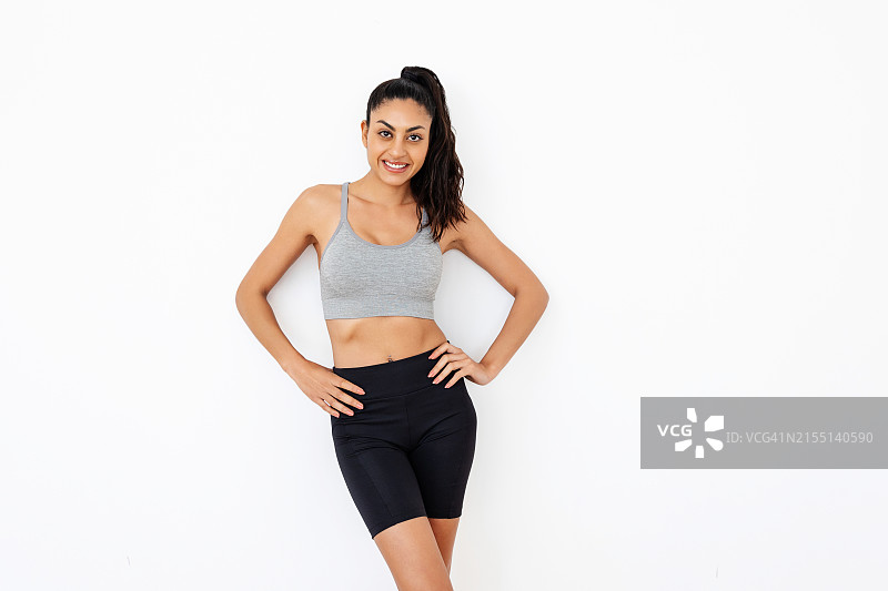 身穿运动服的年轻漂亮女子站在白色工作室墙前图片素材