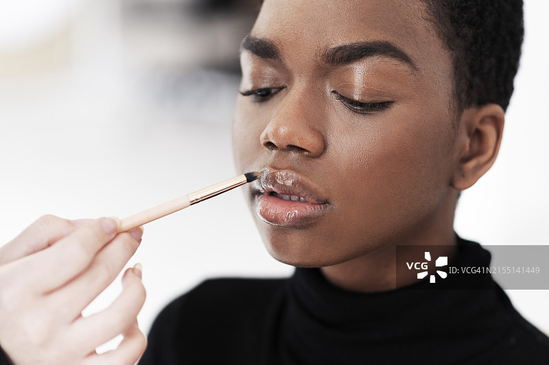 化妆师在工作室用刷子给模特涂唇彩图片素材