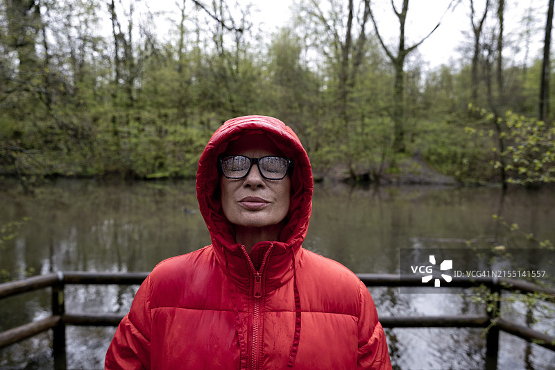 在森林里穿着红色夹克的闭眼女人图片素材