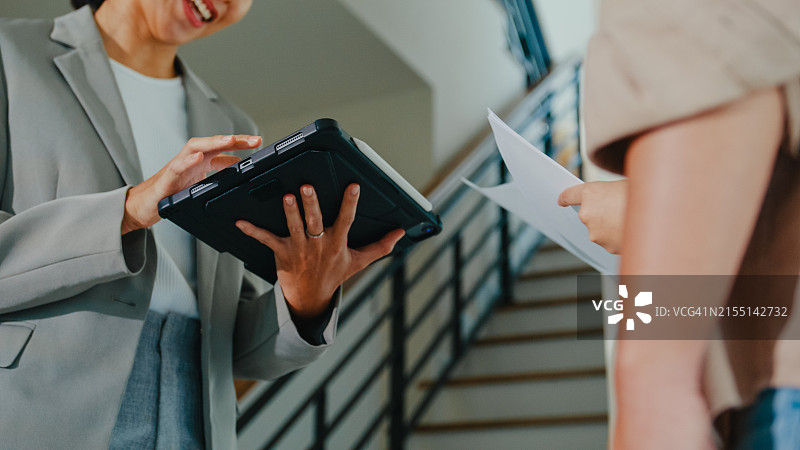亚洲女房地产经纪人向租户解释并展示新房客厅，房东向幸福的夫妇客户出售房地产图片素材