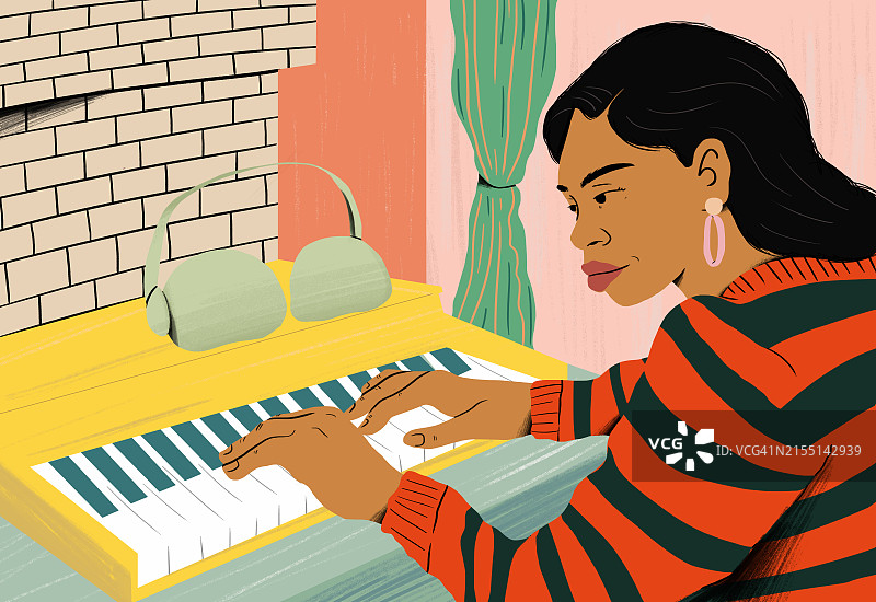 专注的女人戴耳机在桌边弹钢琴图片素材