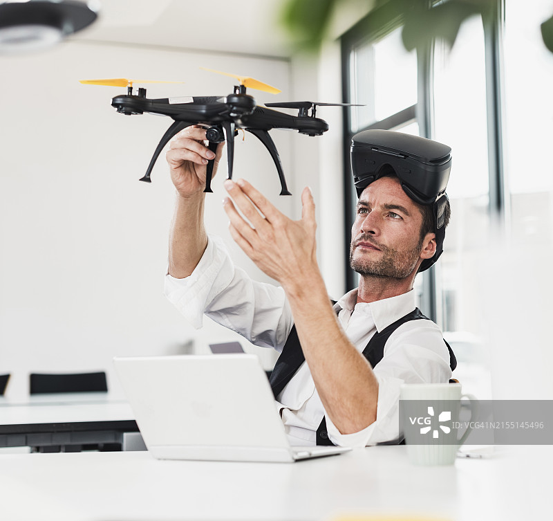 中年商人戴VR眼镜在办公室检查无人机图片素材