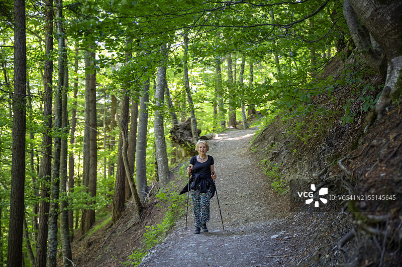 年长的女人在森林中拄着拐杖徒步旅行图片素材