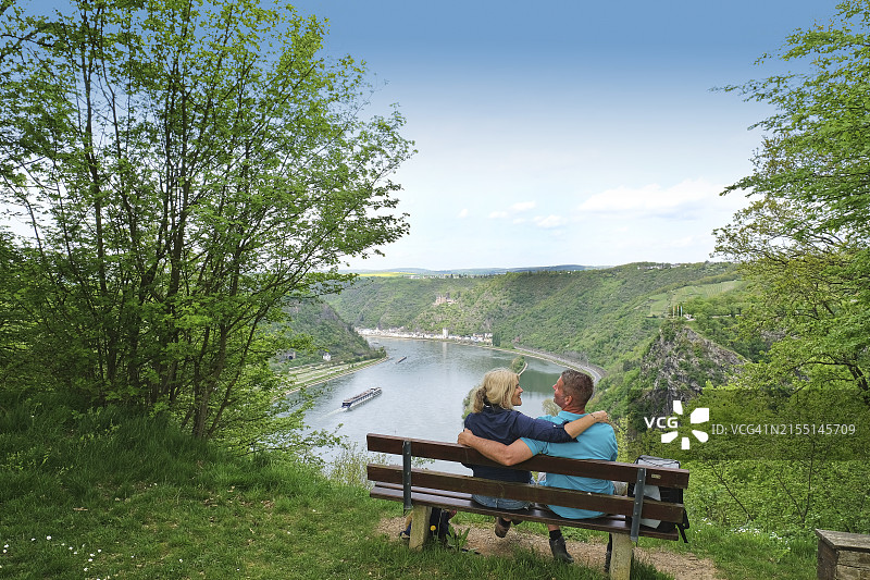 徒步情侣在德国圣戈阿尔斯豪森的洛雷莱岩观景长椅上相拥而坐，莱茵兰-普法尔茨图片素材