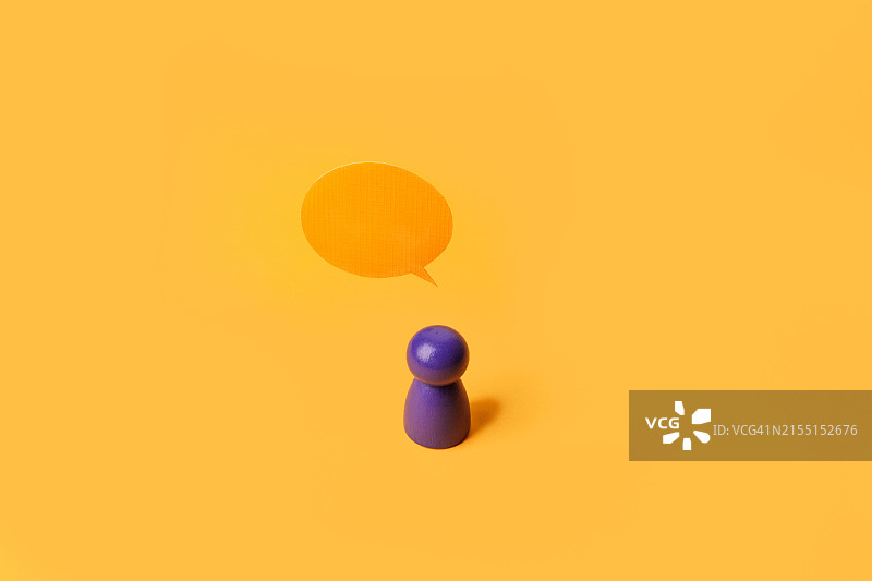 黄色背景上的木制人形玩偶和对话气泡图片素材