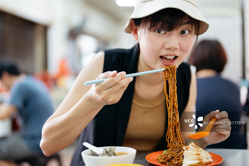 年轻的亚洲女人在当地小吃摊吃馄饨面图片素材