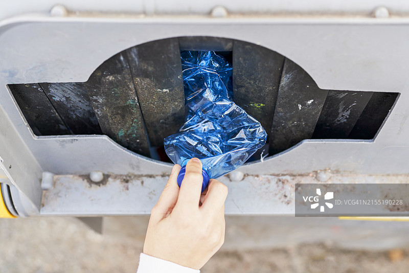 近景后视图：站立的女人将垃圾扔进街道垃圾箱图片素材