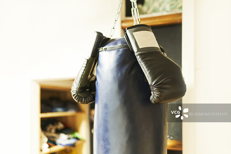悬挂在天花板上的拳击沙袋正面图（带手套，周围无人）图片素材