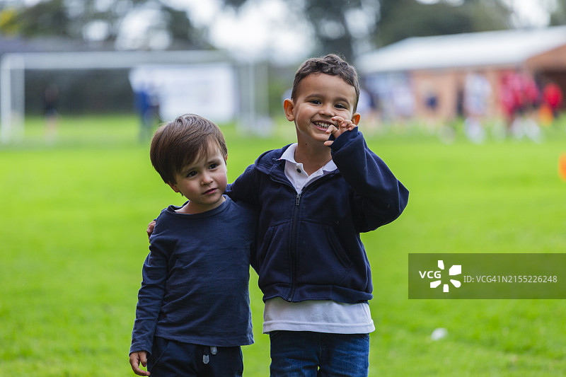 两个拉丁裔儿童在玩极限飞盘，看着镜头图片素材