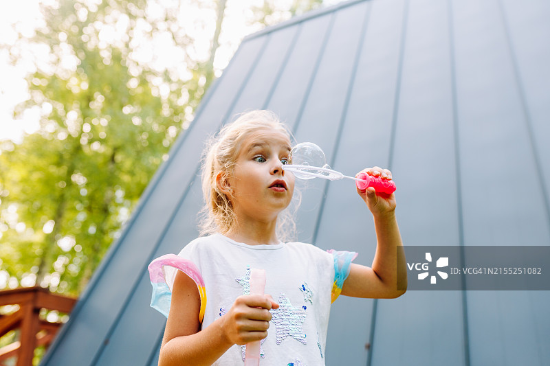 看大肥皂泡！年轻金发女孩在新鲜空气中吹肥皂泡图片素材