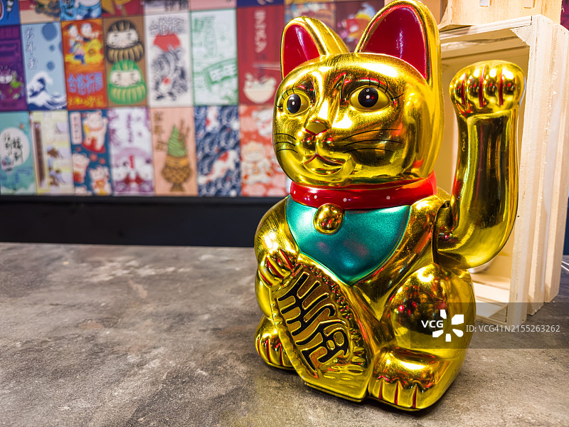 招财猫金色雕像：举爪迎客，象征财富、好运和传统图片素材