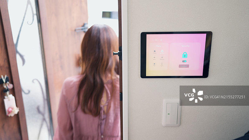 女子离家时使用智能家居安防系统锁门图片素材