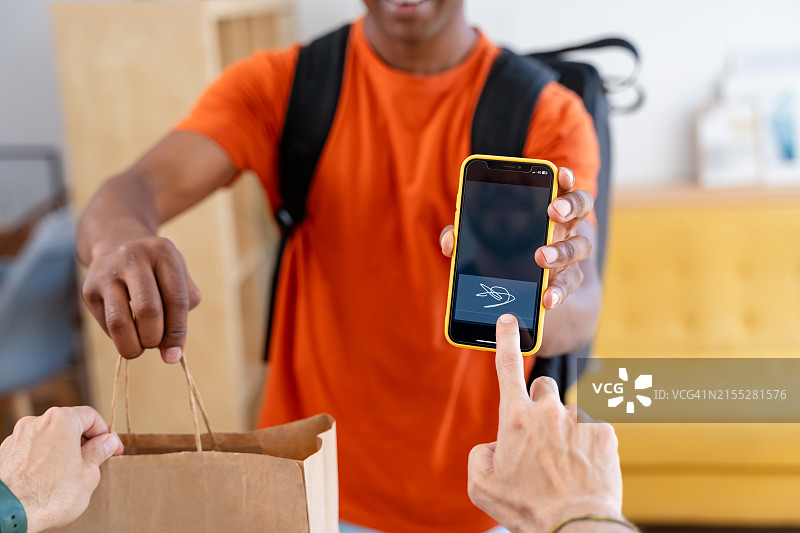 微笑的快递员使用移动应用程序向客户交付包裹，实现流畅的交付过程图片素材