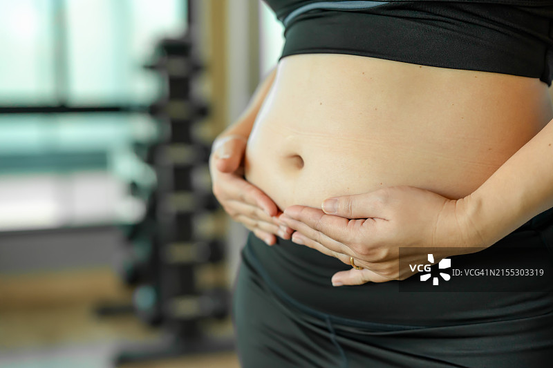 东南亚女性手拿腹部赘肉图片素材