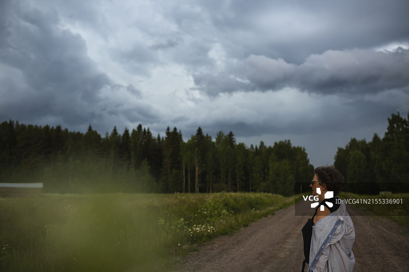 女人站在人行道上看着草地图片素材