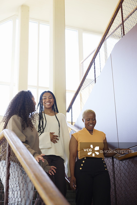 仰视微笑的女性朋友们走下楼梯图片素材