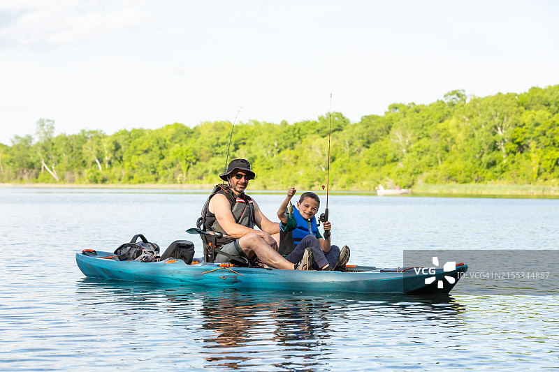 夏季在湖上皮划艇钓鱼的父子图片素材