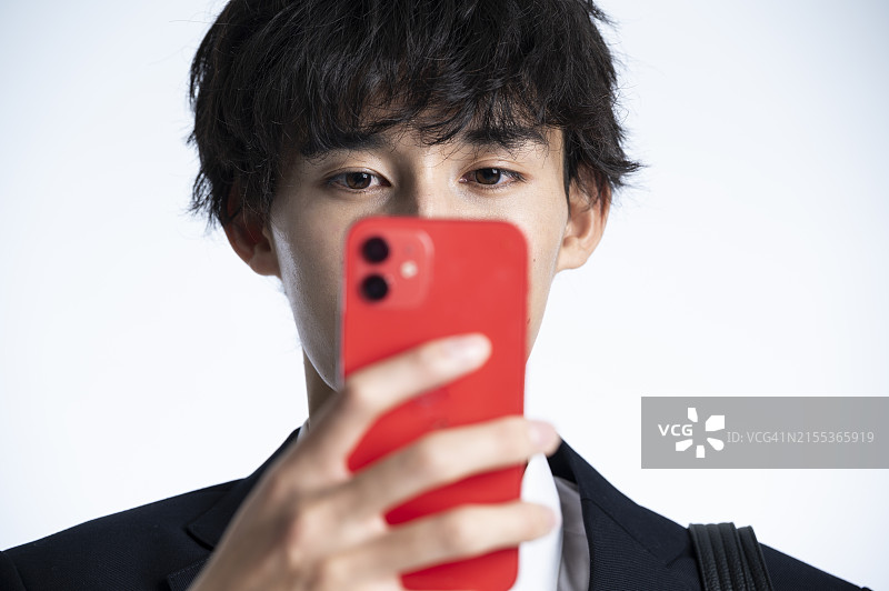 穿制服的日本男高中生正在使用智能手机图片素材