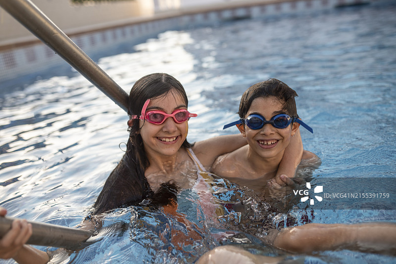 两个快乐的兄弟戴着潜水镜在夏日泳池里玩耍图片素材