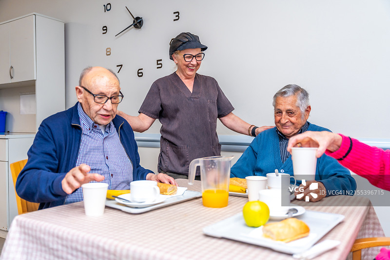 女人在养老院为老年人提供早餐并交谈图片素材