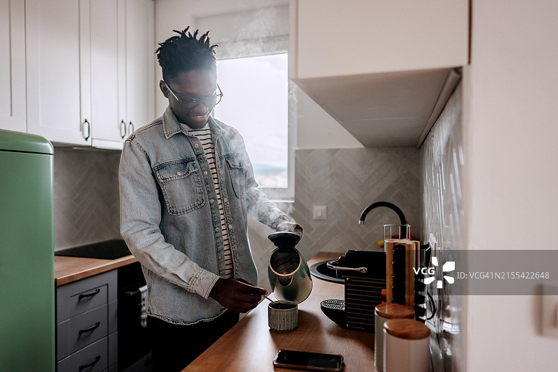 在家里厨房做咖啡的穿着休闲的年轻男人图片素材