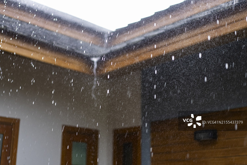 暴雨和大风吹袭屋顶，倾盆大雨的特写，极端气候概念图片素材