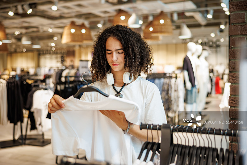 在购物中心挑选衣服的男孩图片素材