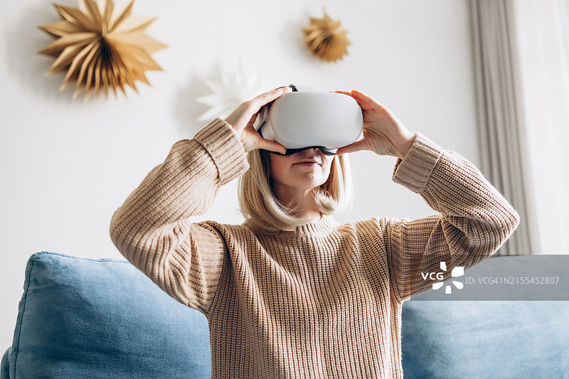 年轻女人在家中使用虚拟现实眼镜图片素材