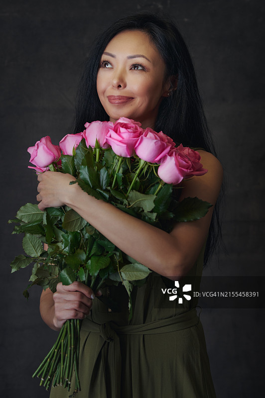 在工作室里，手捧红粉玫瑰花束的女人，背景为画布图片素材