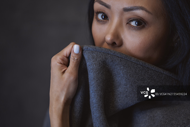 身穿灰色外套的女人在工作室的画布背景前图片素材